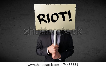Businessman holding a demonstration board with riot sign in front of his head