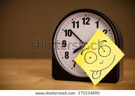 Drawn smiley face on a note sticked on an alarm clock