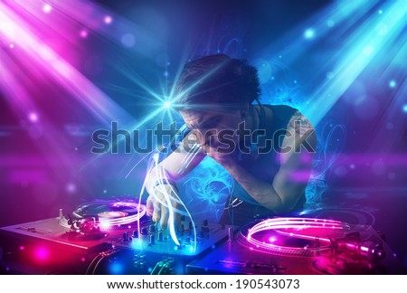 Young energetic Dj mixing music with powerful light effects