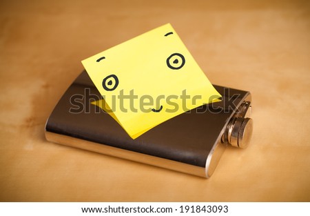 Drawn smiley face on a post-it note sticked on a hip flask
