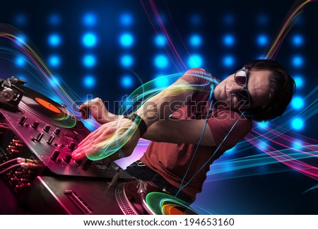 Attractive young Dj mixing records with colorful lights