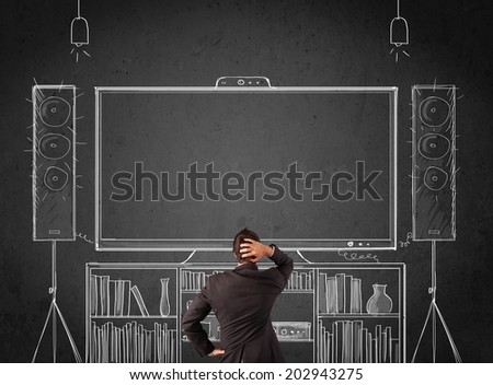 Young businessman standing and enjoying home cinema system sketched on a chalkboard