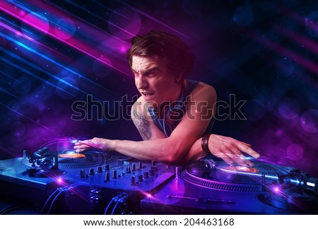 Attractive young DJ playing on turntables with color light effects
