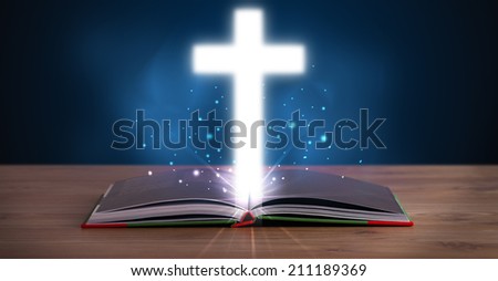 Open holy bible with glowing cross in the middle on wooden deck Open holy bible with glowing cross in the middle on wooden deck