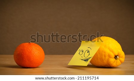 Lemon with sticky post-it note reacting at orange