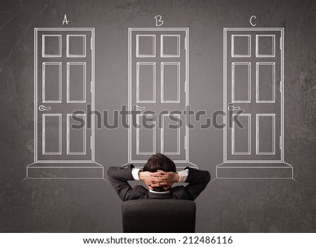 Young businessman sitting in front of a chalkboard and trying to choose the right door