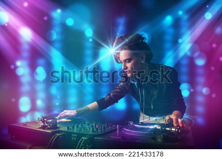 Pretty Dj mixing music in a club with blue and purple lights