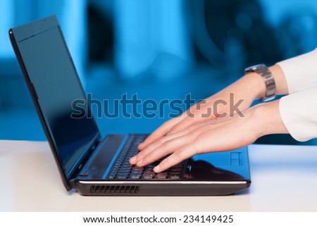 Businessman pressing modern laptop computer on colorful office background