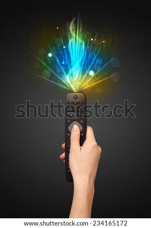 Hand holding a remote control, shining and explosive signal coming out of it