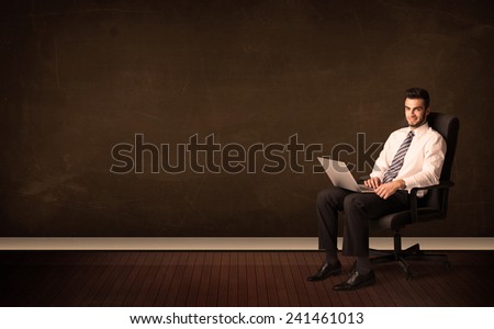 Businessman holding high tech laptop on brown background with copyspace