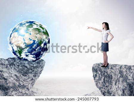 Businesswoman standing on the edge of mountain with a globe on the other side \