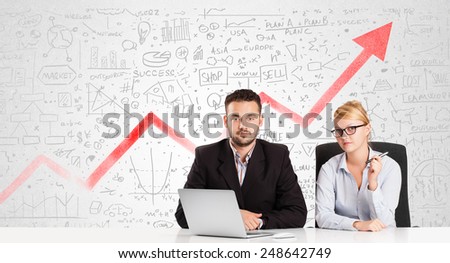 Business man and woman sitting at table with market hand drawn diagrams