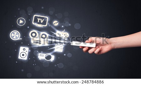 Hand holding a remote control, media icons coming out of it