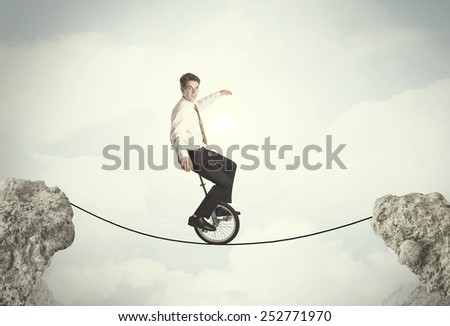 Brave business man riding an mono cycle between cliffs concept