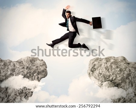 Happy business man jumping over a cliff concept