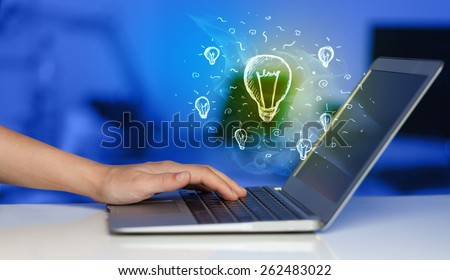 Close up of hand with laptop and glowing idea bulb