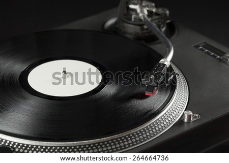 Turntable playing vinyl close up with needle on the record with grey background