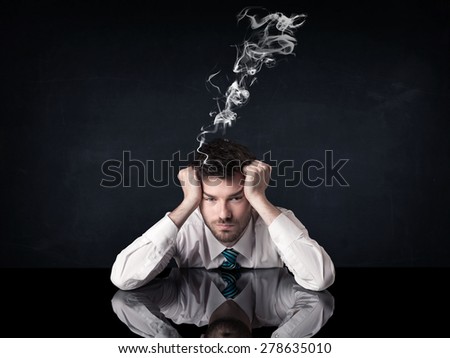 Young depressed businessman sitting with smoking head