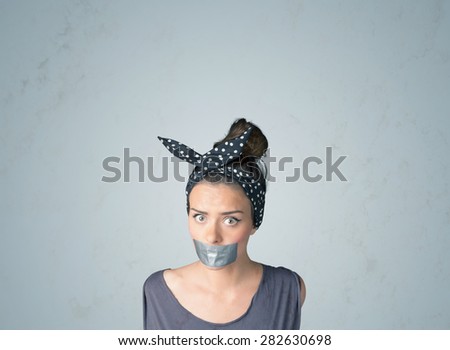 Young woman with taped mouth. Isolated on the gray background