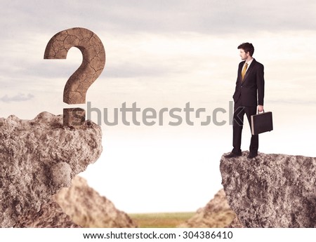 Businessman standing on the edge of mountain with a rock question mark on the other side