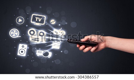 Hand holding a remote control, media icons coming out of it
