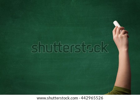 A mature hand writing or drawing on a clean green blackboard with a white chalk.