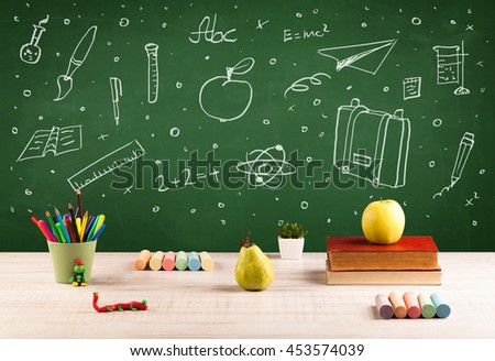 Wooden school desk with stuff and blackboard full of drawings concept