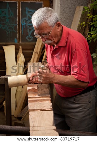 Old woodcarver working with mallet and chisel 3