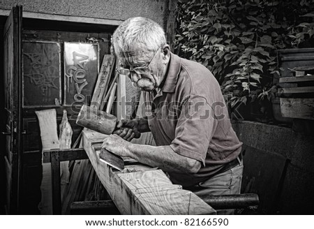 Old woodcarver working with mallet and chiesel, vintage style