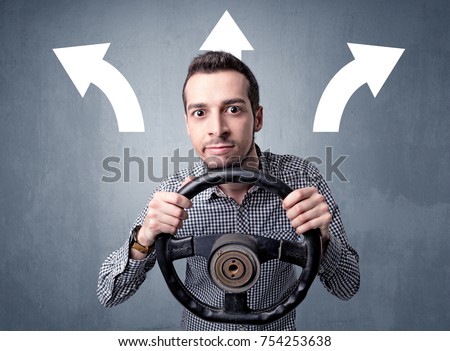 Young man holding black steering wheel with three arrows above his head pointing in different directions