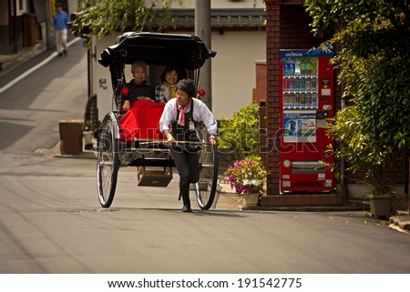 KYOTO, JAPAN - MAY 9: Two women in a rickshaw pulled by a young tour guide on a street in Kyoto, Japan on 9th May 2010. The Rickshaws are a popular way to tour the city.