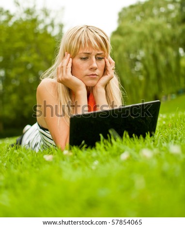 Young blond woman with laptop in the park
