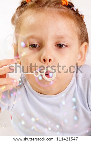 Attractive little girl blowing soap bubbles