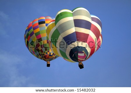 Two hot air balloons ascending into a clear blue sky