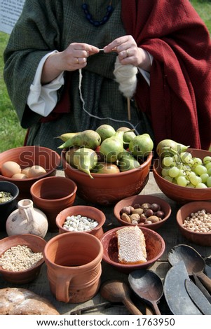Roman Lady knitting and a display of food on the table