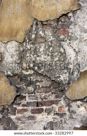 Crumbling cement reveals a layer of plaster then layers of brick