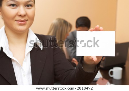 young businesswoman holding blank card, business people at the back, shallow dof