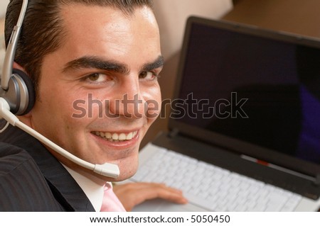 young happy businessman ready to help with a headset and laptop
