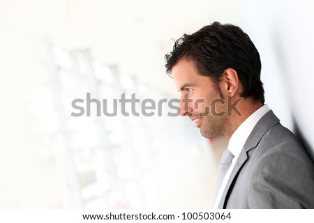 Businessman standing on white wall- profile view