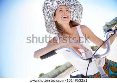 Beautiful woman with hat riding bike in Miami beach