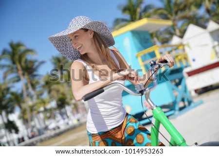 Beautiful woman with hat riding bike in Miami beach