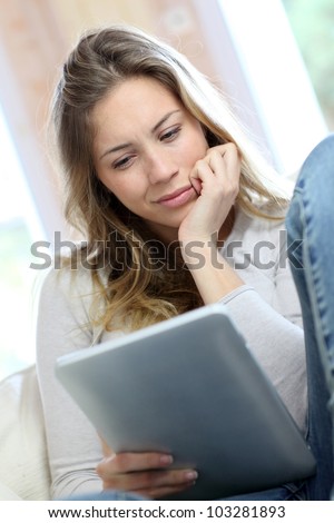 Young woman looking at electronic tablet with puzzled look