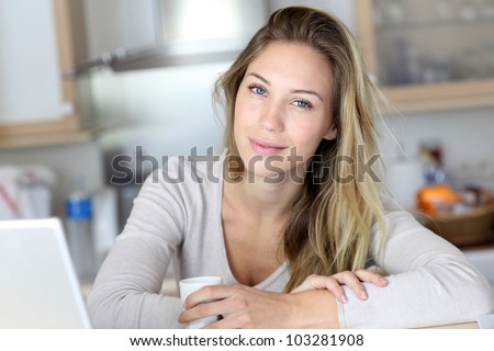 Woman checking email on laptop computer while drinking coffee