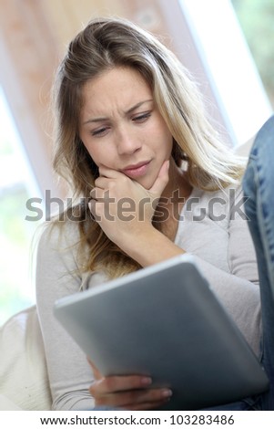 Young woman looking at electronic tablet with puzzled look