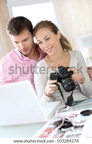 Couple at home looking at pictures on camera and laptop