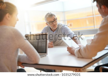 Teacher meeting around table with students