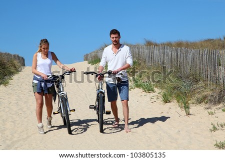 Couple walking on a sandy path with bicycles