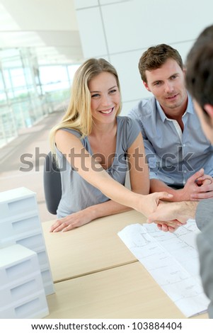 Couple shaking hand to real-estate agent in office