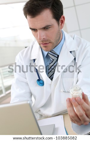 Doctor with laptop computer checking medicine composition
