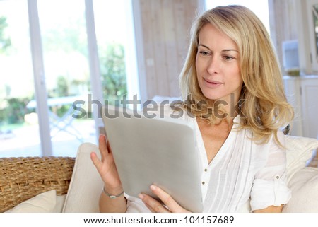 Beautiful mature woman using electronic tablet at home